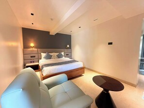 A modern bedroom with a bed, bedside tables, a sofa, and a small table. - Palette Hotel Maneraa by CheckIn (Tirupati)