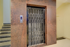 An elevator with a metal gate, a digital display, and a control panel. - Hotel O RB Comfort (Hyderabad)
