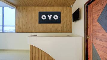 A reception desk with a sign that reads 'OYO' against a wooden wall.