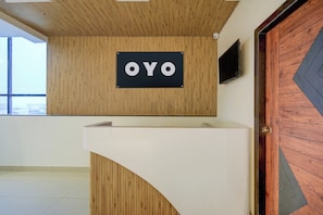 Una mesa de recepción con un letrero que dice 'OYO' frente a una pared de madera.