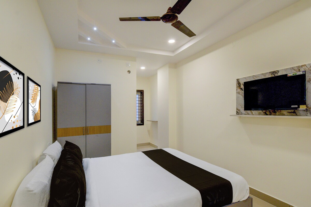 A hotel room with a bed, a wardrobe, a ceiling fan, a window with a view, and framed artwork on the wall.