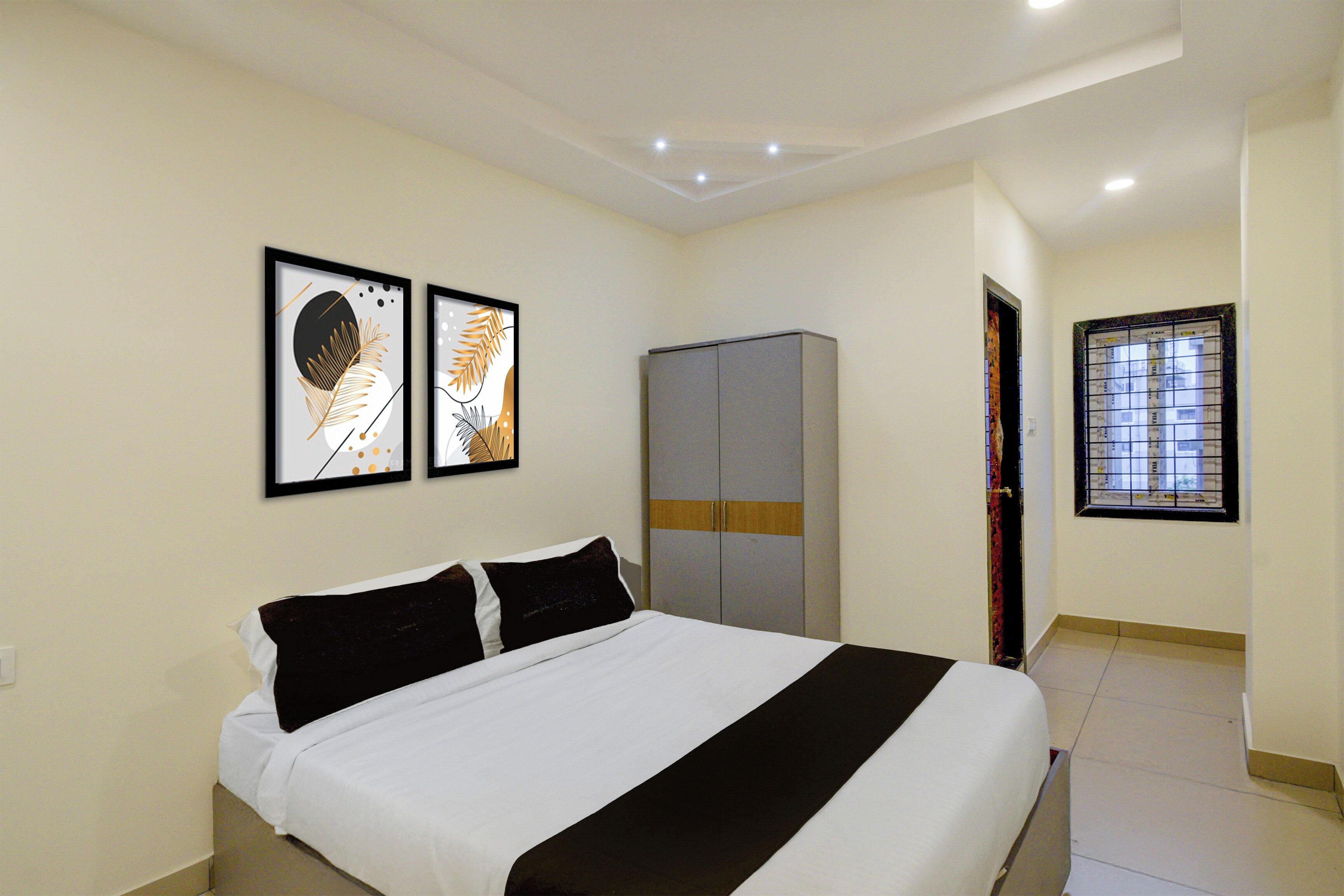 A bedroom with a bed, a wardrobe, and two framed artworks on the wall.