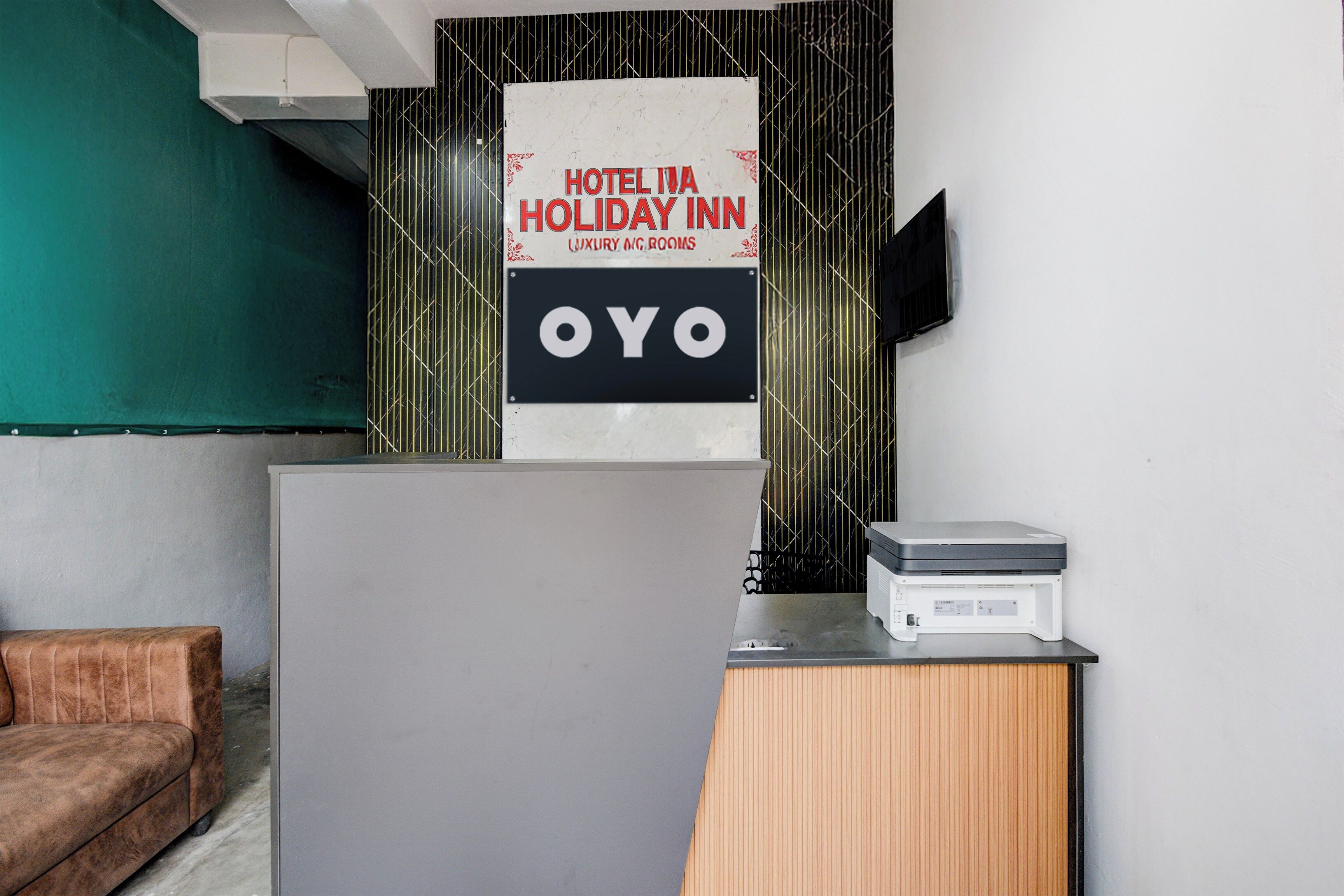 A reception desk with a sign for 'Hotel IVA Holiday Inn Luxury A/C Rooms' and a logo 'OYO'.