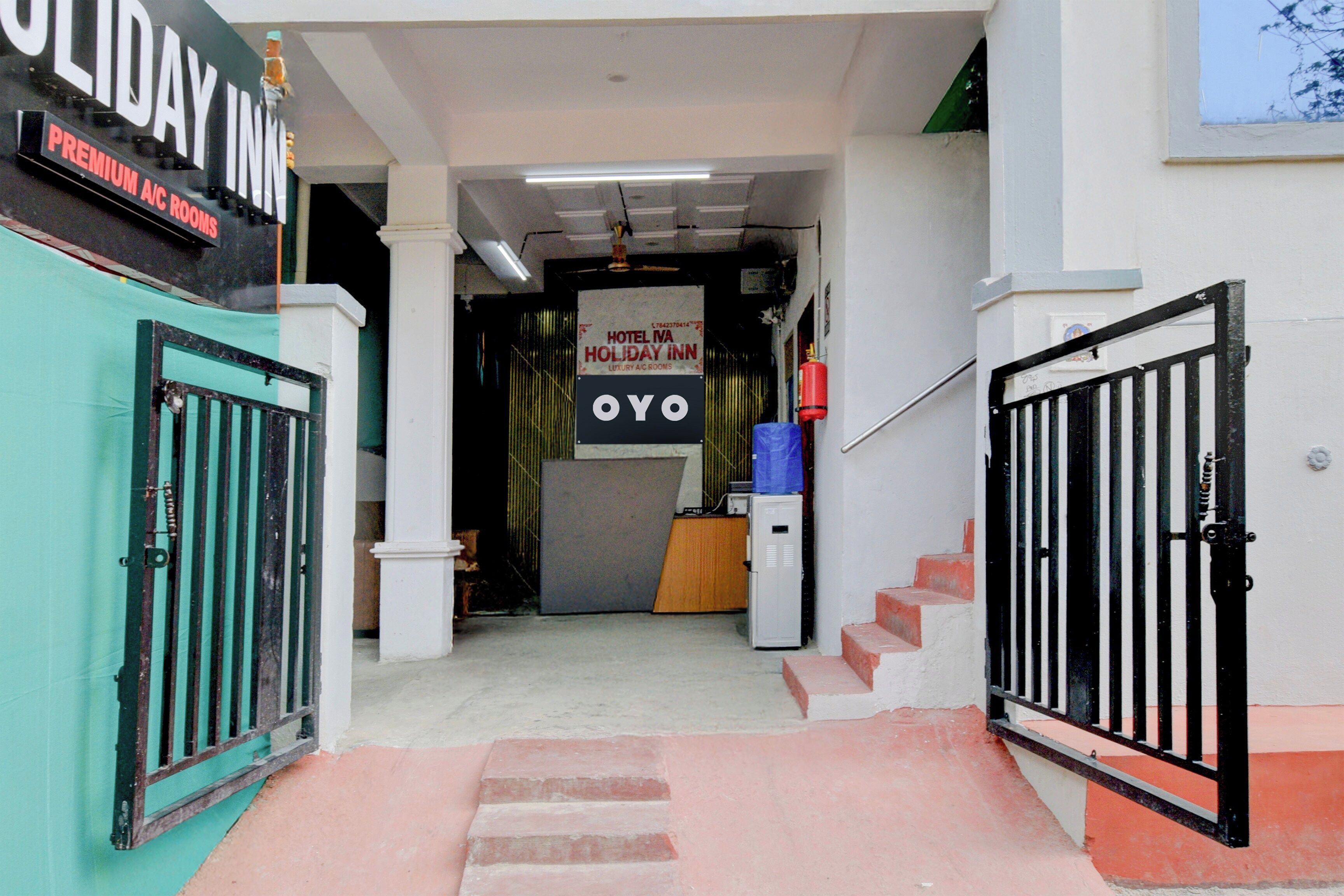 A hotel entrance with a sign for 'HOTEL NANN HOLIDAY INN' and 'OYO' branding, a fire extinguisher, and a staircase leading to the interior.