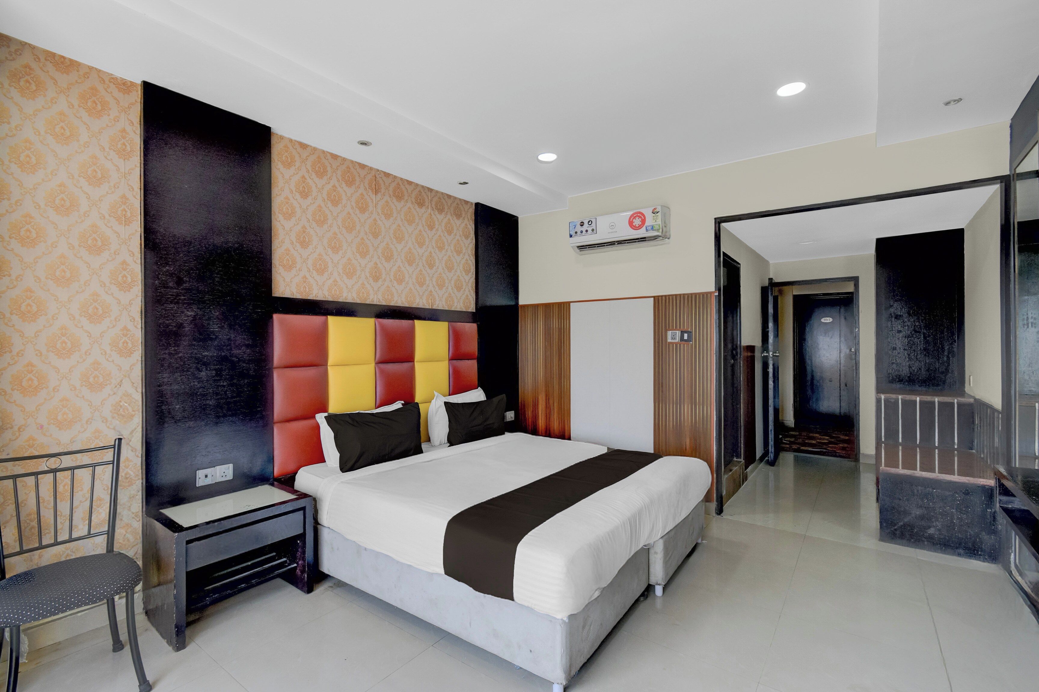 Una habitación de hotel con una cama grande, una mesita de noche, una silla y un armario.