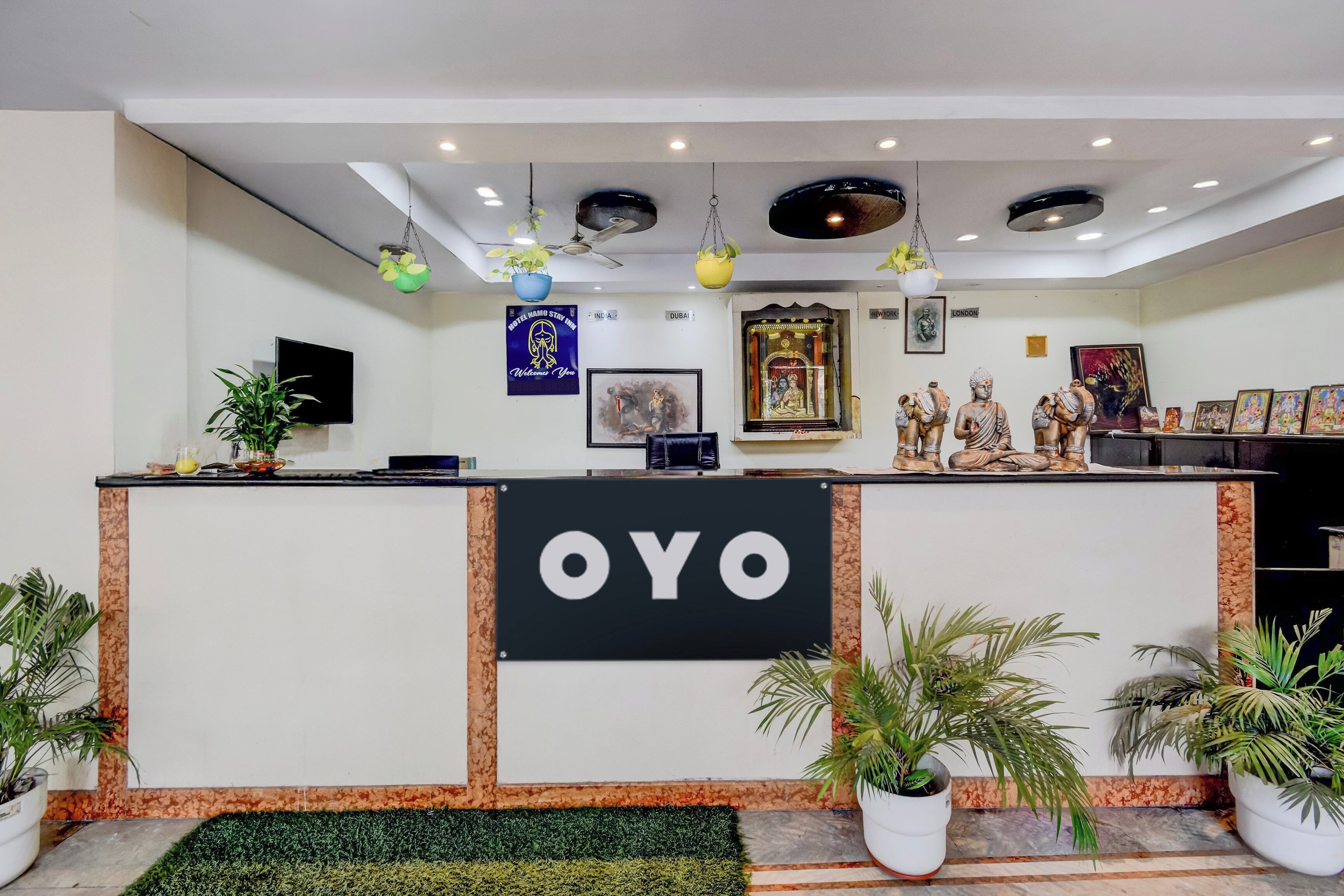 Una mesa de recepción con un cartel que dice 'OYO' y una pared con cuadros enmarcados y una estatua.
