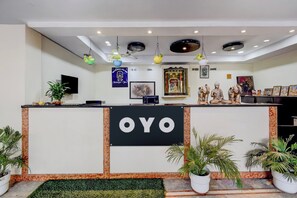 Una mesa de recepción con un cartel que dice 'OYO' y una pared con cuadros enmarcados y una estatua.