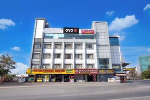 A hotel with multiple floors, a prominent sign for 'OYO Hotel', and several storefronts including 'Raghavendra Bhavan' and 'Santosh Dhaba'. - Hotel O Namo Stay Inn (Hyderabad)
