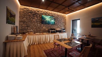 Un comedor con pared de piedra, televisor de pantalla plana, mesas de buffet y alfombra estampada.