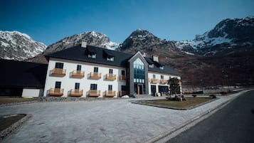 Un hotel con fachada blanca, varios balcones y un acceso empedrado.