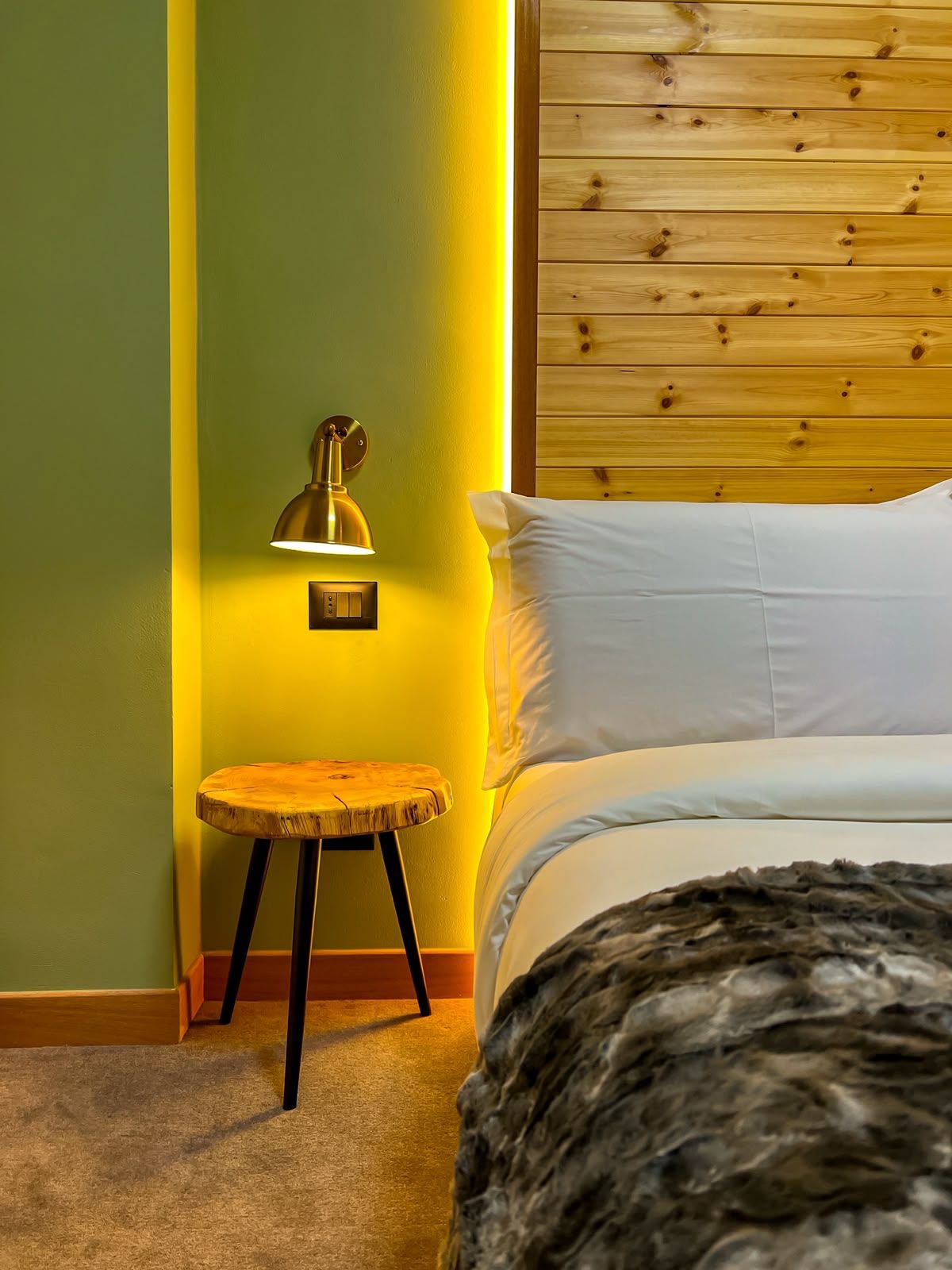 A bedroom with a bed, a nightstand, a lamp, and a wooden headboard.