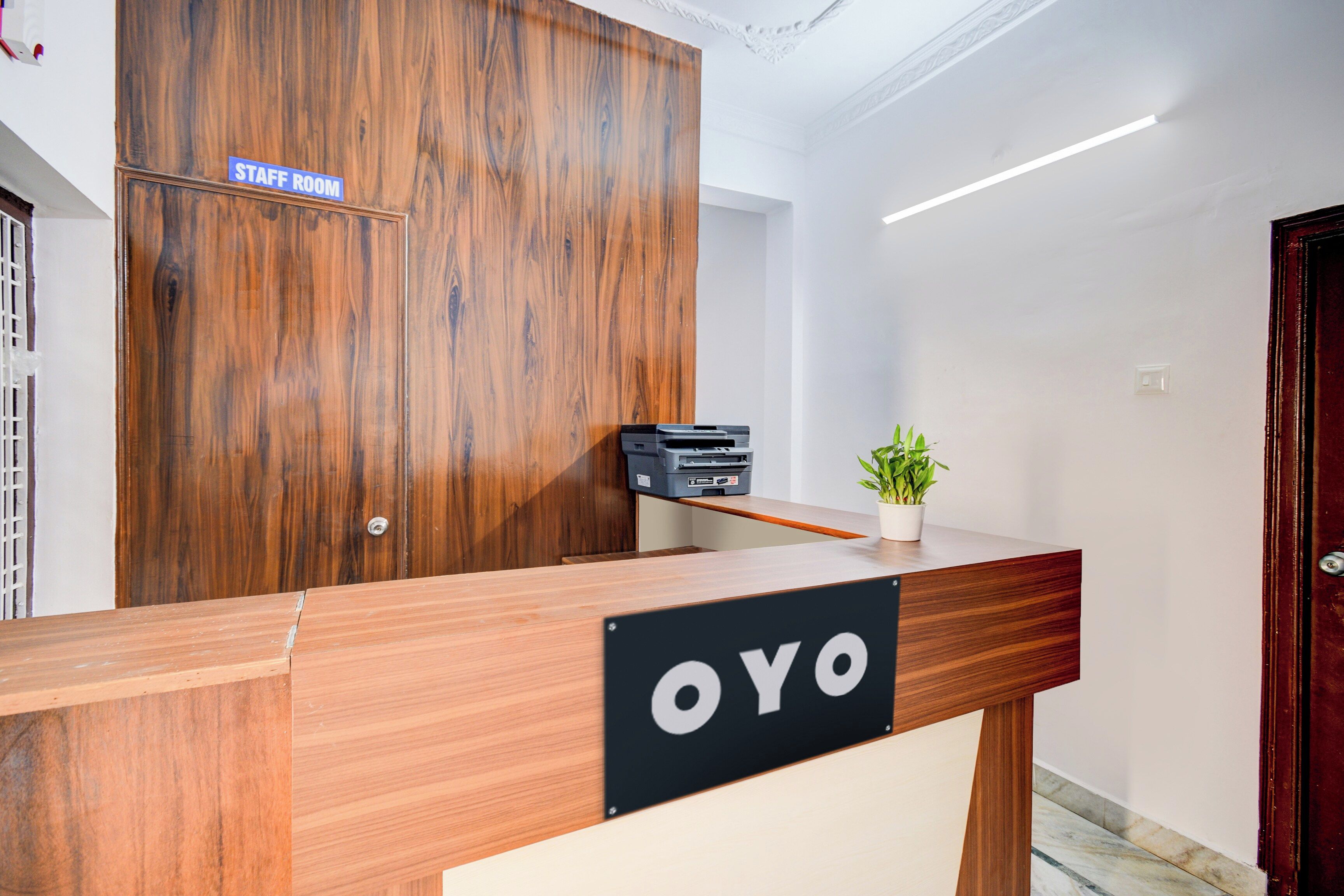 A reception desk with a sign that reads 'OYO' and a 'STAFF ROOM' sign above a wooden door.