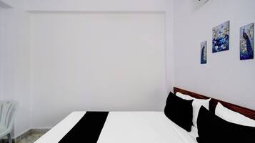 Ein Schlafzimmer mit einem Bett, einem Sessel und drei an der Wand hängenden Bildern.