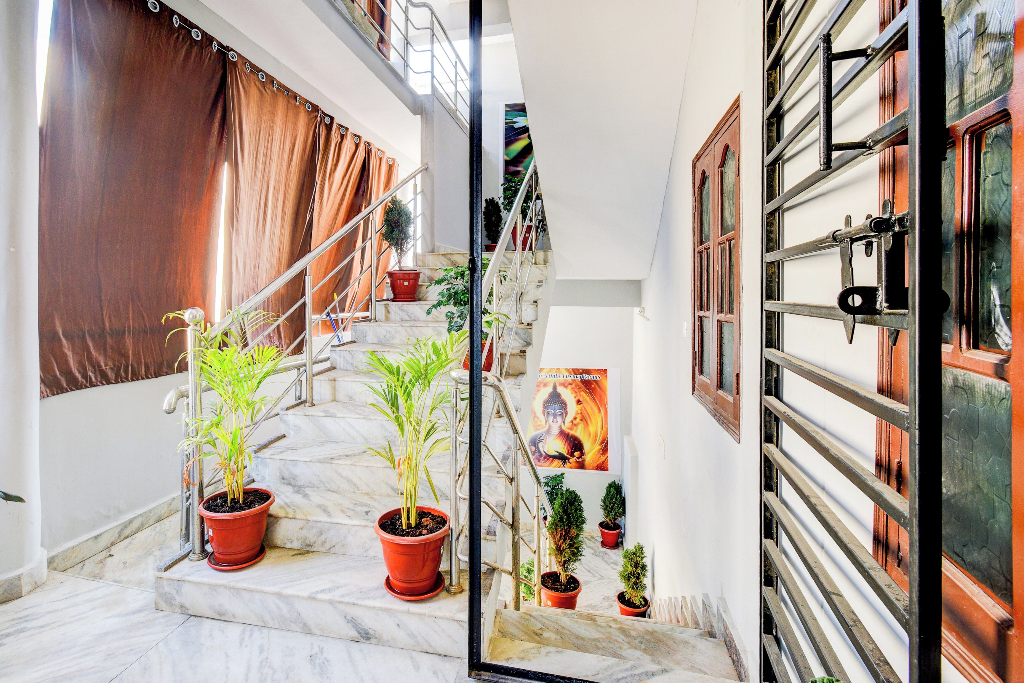 A staircase with potted plants, a metal railing, and a poster on the wall.
