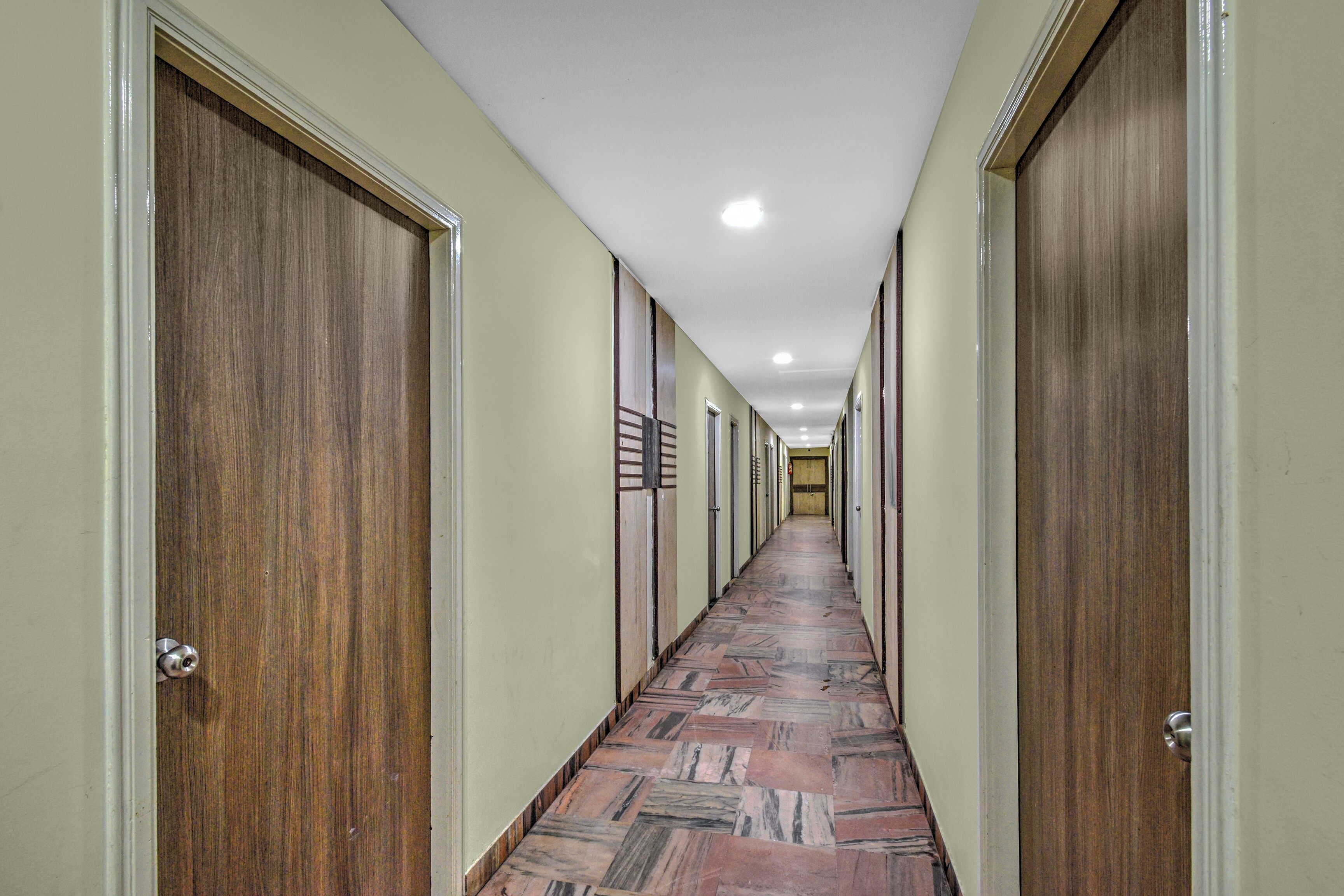 A long hallway with wooden doors on both sides and a patterned floor.