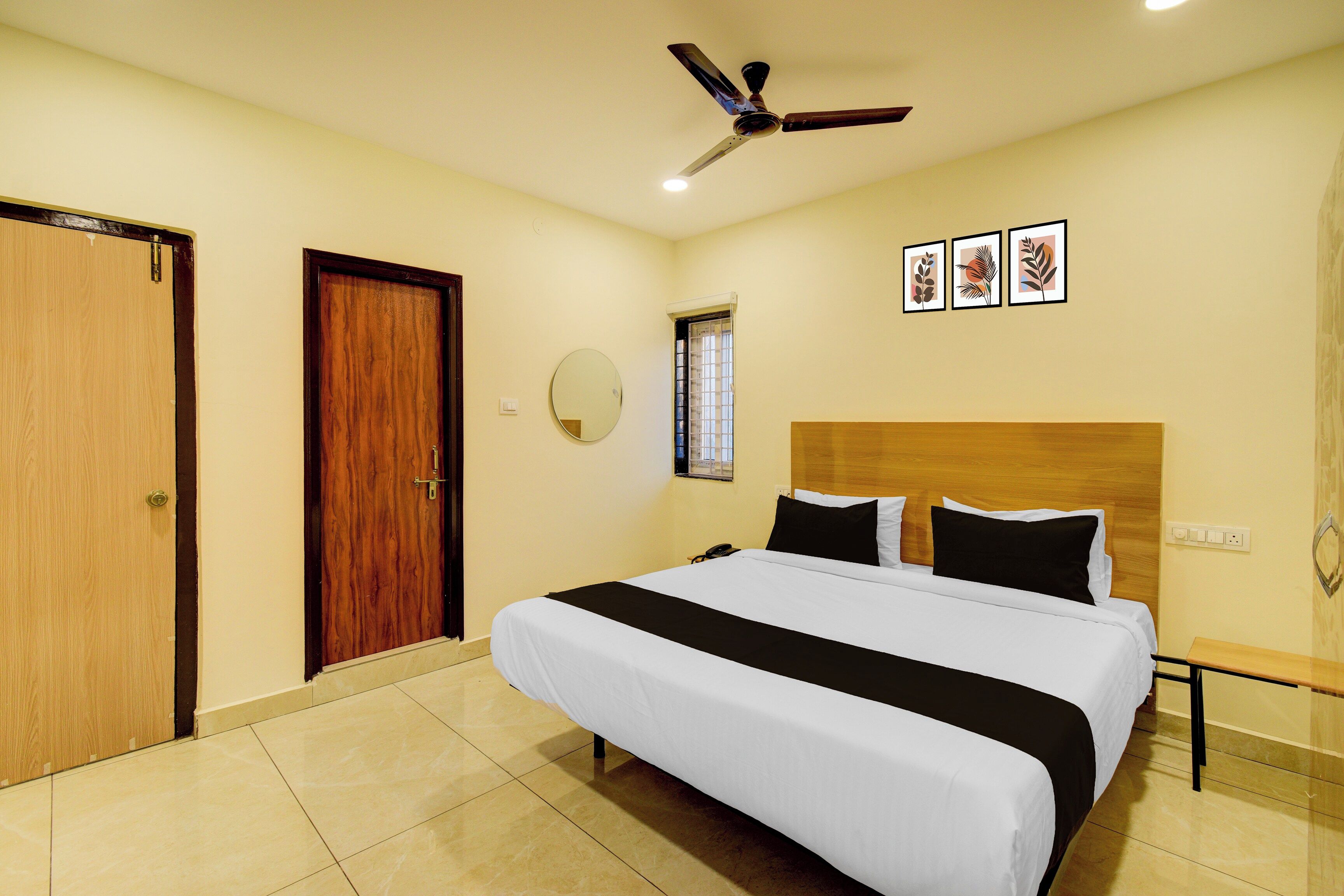 A hotel room with a bed, a ceiling fan, a window, and a door.