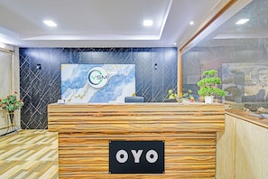 A reception desk with a wooden finish and a black sign reading 'OYO'. - Hotel O VSM Suites (Hyderabad)