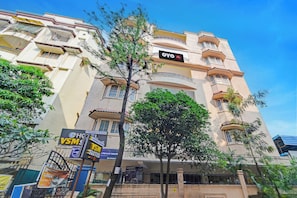 A multi-story hotel with balconies, a prominent OYO sign, and various advertisements including VSM and a private theater. - Hotel O VSM Suites (Hyderabad)