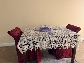Ein Tisch mit weißer Spitze, zwei violette Dekorplatten und eine Schachtel darauf.