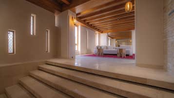 Habitación de hotel con techo de madera, una cama con alfombra roja y una escalera que conduce al piso superior.