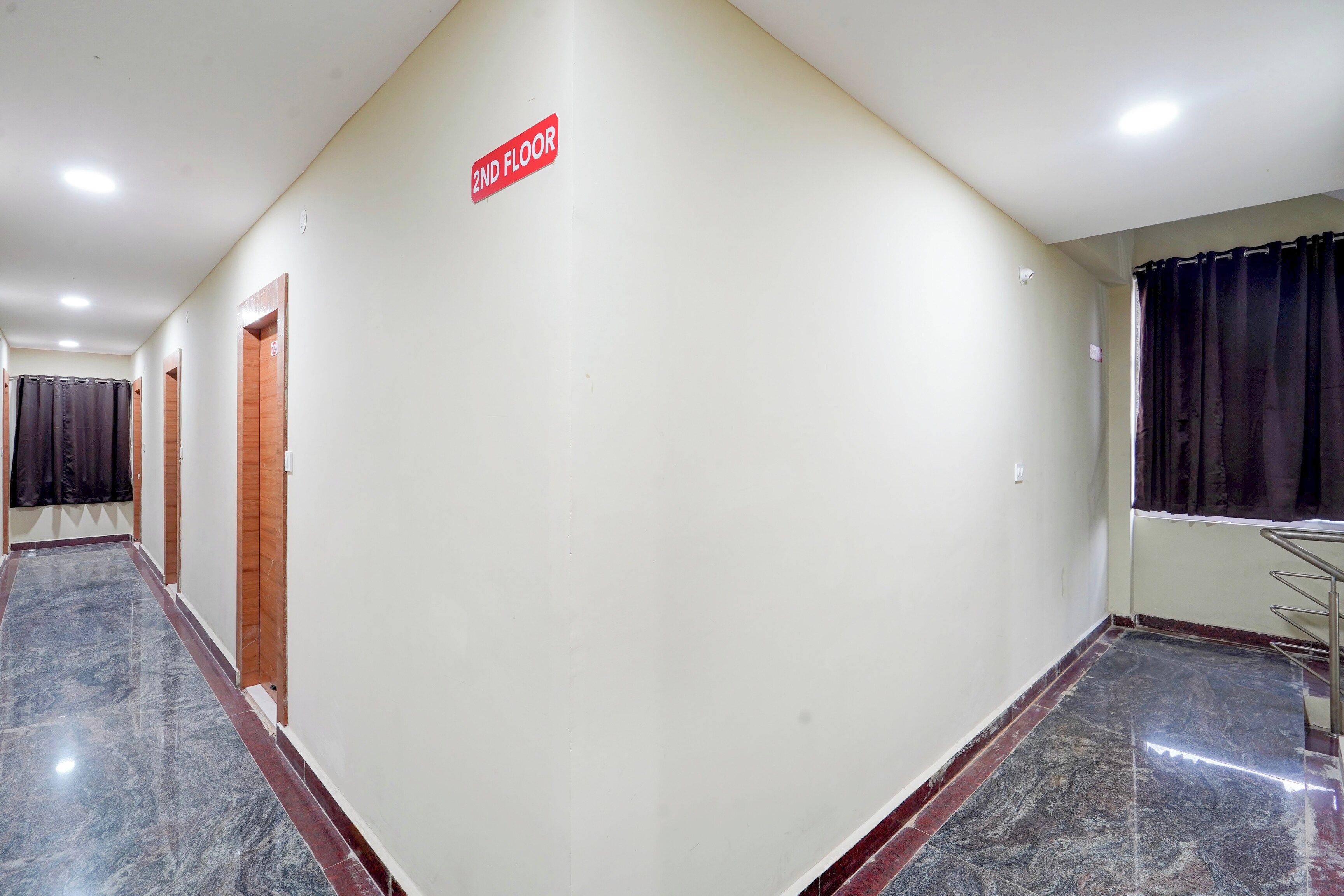 A hallway with a sign indicating the 2nd floor, a door, and a window with curtains.