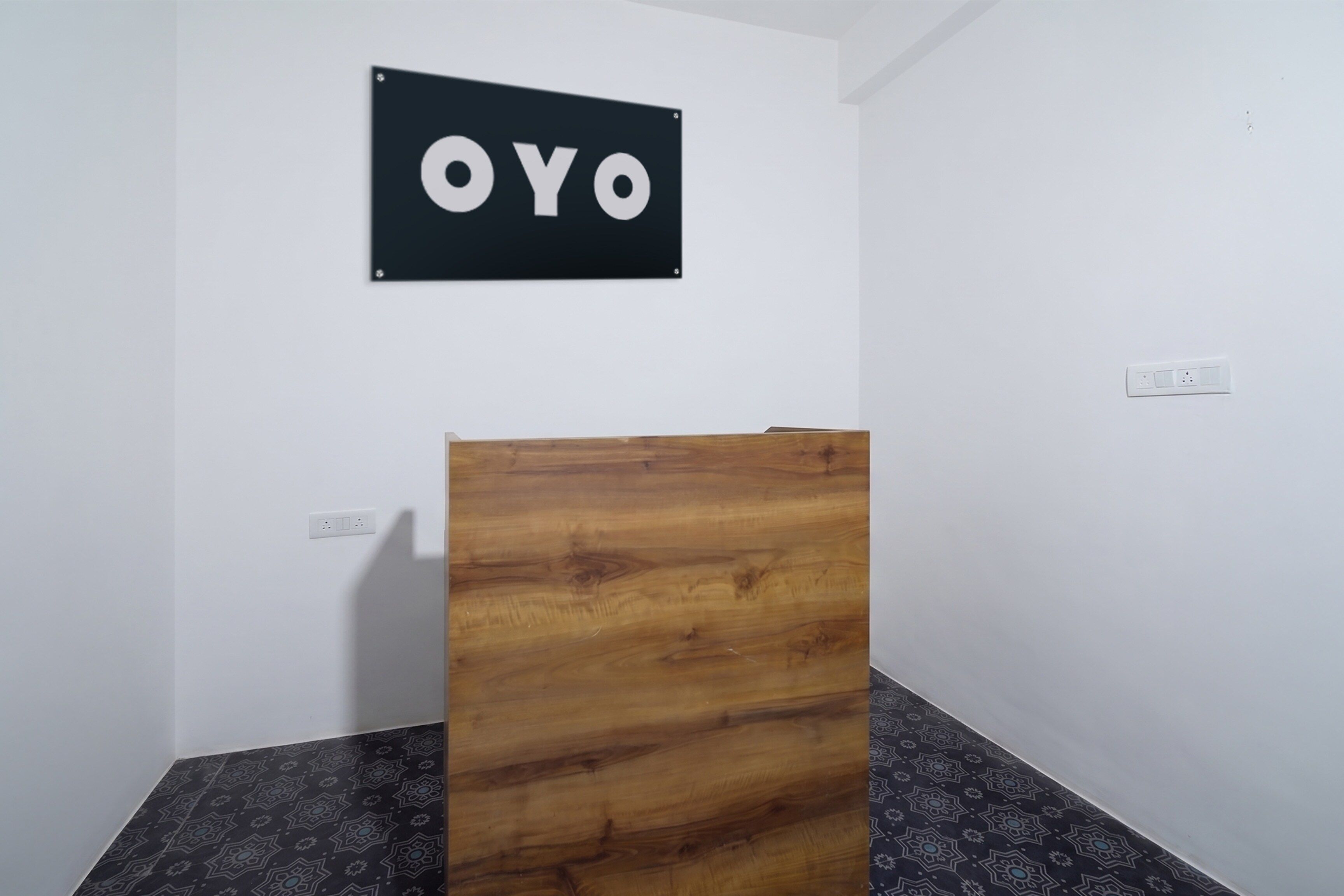 A room with a wooden partition, a wall-mounted sign reading 'OYO', and a power outlet.