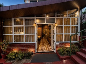 A hotel entrance with a brick facade, large windows, and a patterned floor leading inside. - Hotel R.J. House (Abu Road)
