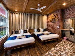 A hotel room with two beds, wooden flooring, a brick accent wall, a ceiling fan, and a window with curtains. - Hotel R.J. House (Aburaj)