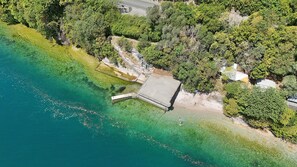 Vista aérea de una propiedad costera con muelle, agua cristalina y abundante vegetación.