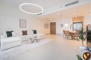 A modern living room with a sofa, coffee table, and dining area with chairs and a table. - Vogue | Maritime City Seagate at Yacht & Marina (Dubai)