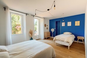Une chambre avec deux lits, une grande fenêtre et une porte donnant sur un balcon.