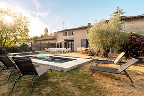 Un jardin avec une piscine, des chaises longues et un espace patio.