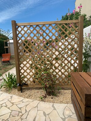 A wooden lattice fence with climbing plants, a stone patio, and a wooden bench. - New Listing (Châtelaillon-Plage)