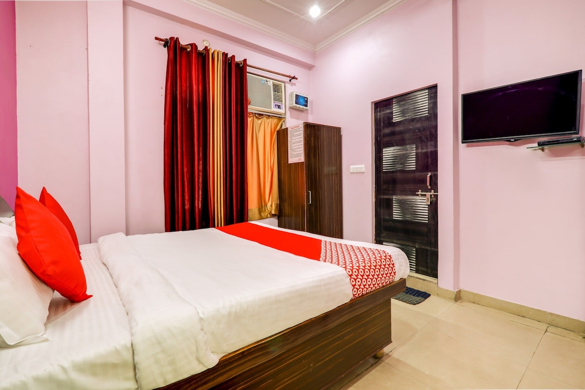 Habitación de hotel con cama, televisor, armario y ventana con cortinas.