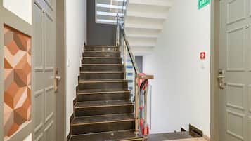 A staircase with a handrail, a door with an exit sign, and a fire alarm.