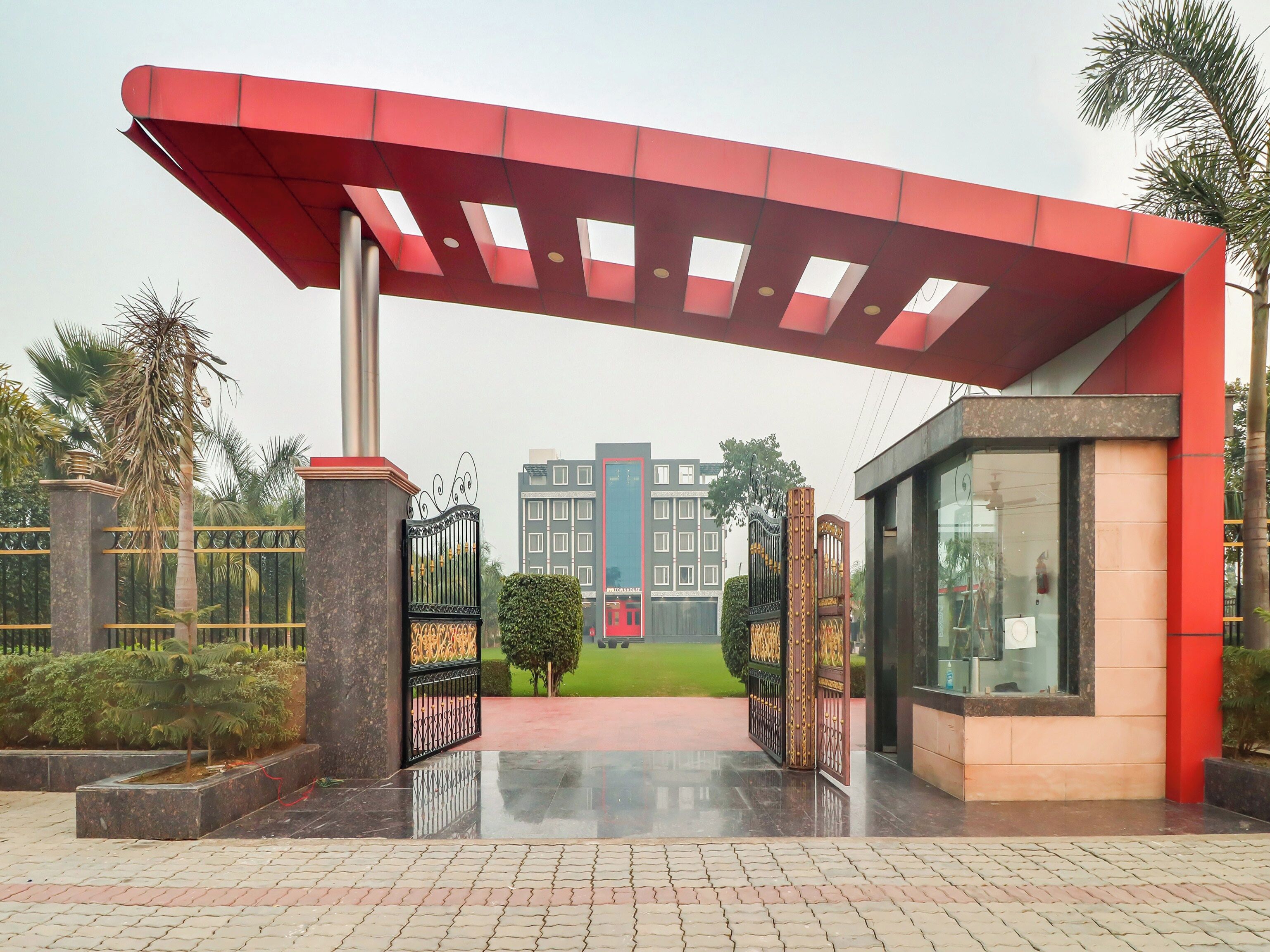 A gated entrance with a red canopy, a paved pathway, and a building in the background.