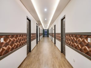 Un pasillo de hotel con puertas a ambos lados, un diseño de pared estampado y suelo de madera.