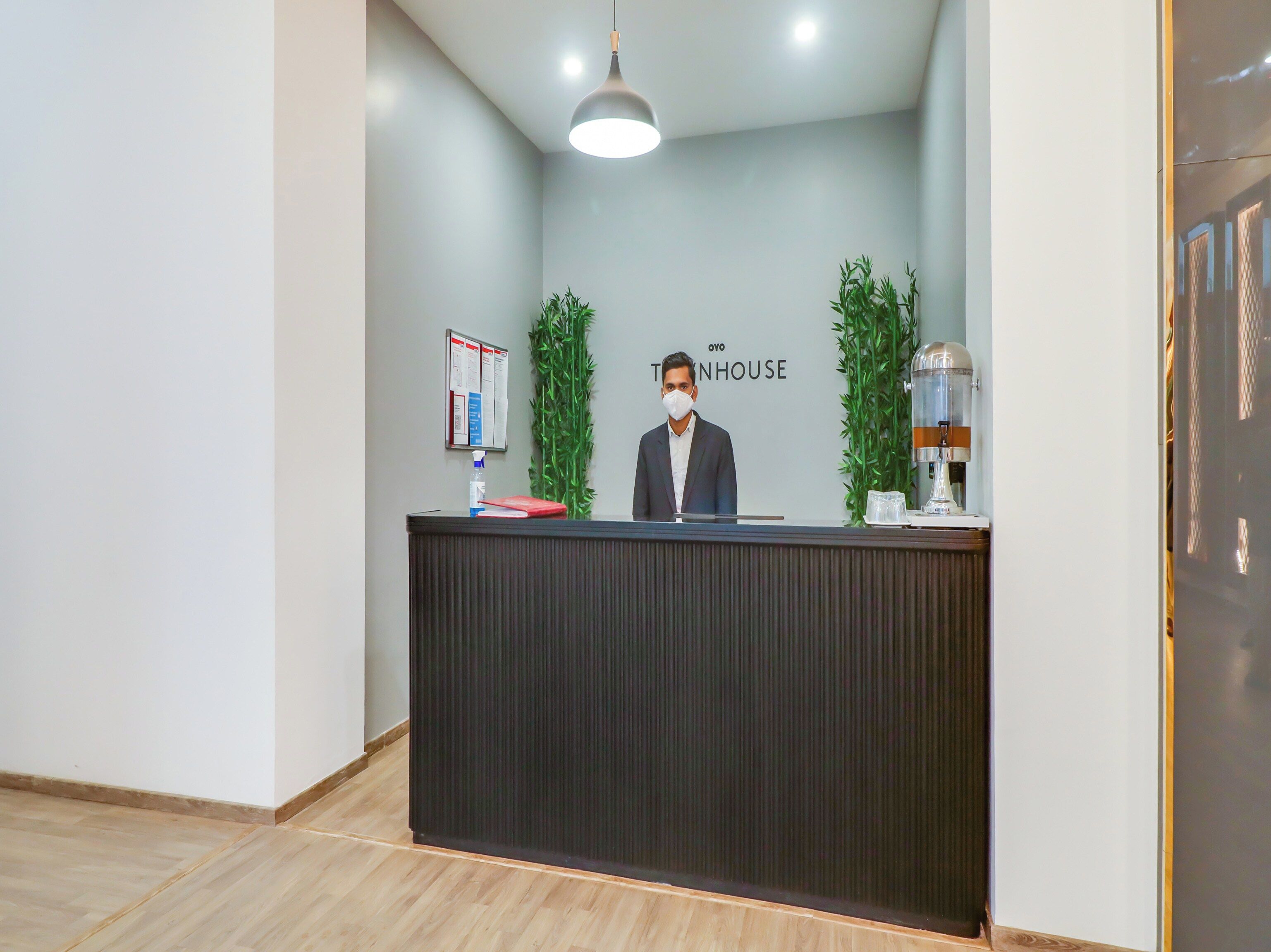 Una recepción con un hombre de pie detrás, una pizarra de anuncios y una máquina de café.