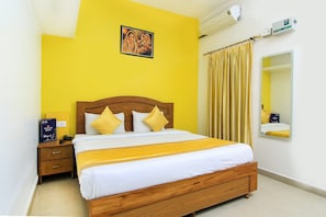 A hotel room with a wooden bed, a nightstand, a mirror, and a wall-mounted air conditioner. - HOTEL O JMD INN (Lucknow)
