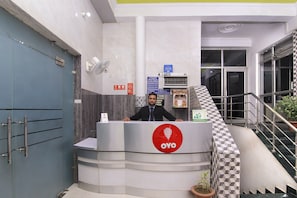 A hotel reception desk with a sign reading 'OYO' and a staircase leading to an upper level. - HOTEL O JMD INN (Lucknow)