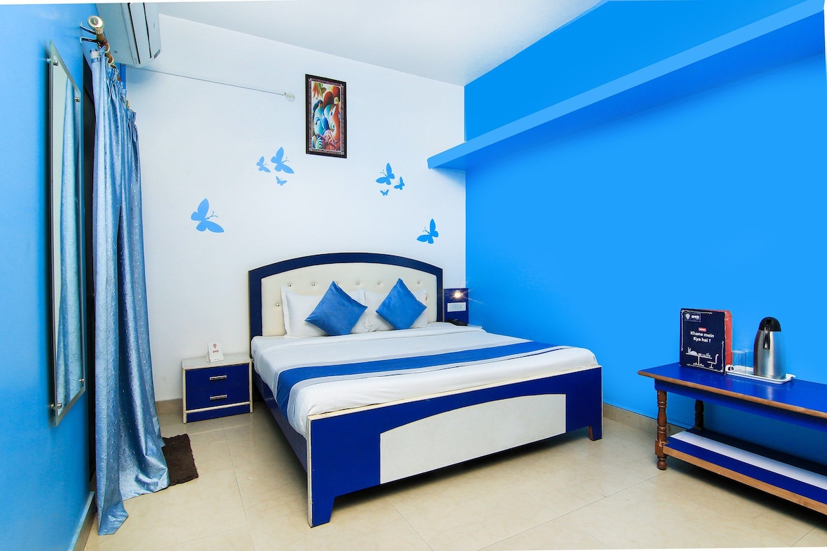 A bedroom with a bed, nightstand, and a table with a kettle.