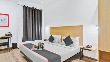 Una camera d'albergo con un letto, un comodino e una scrivania con una sedia.