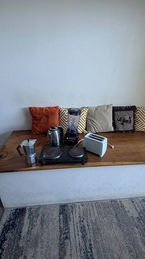 A kitchen area with a coffee maker, blender, kettle, toaster, and a wooden countertop. - Beachside Studio With Rooftop Views (Jacó)