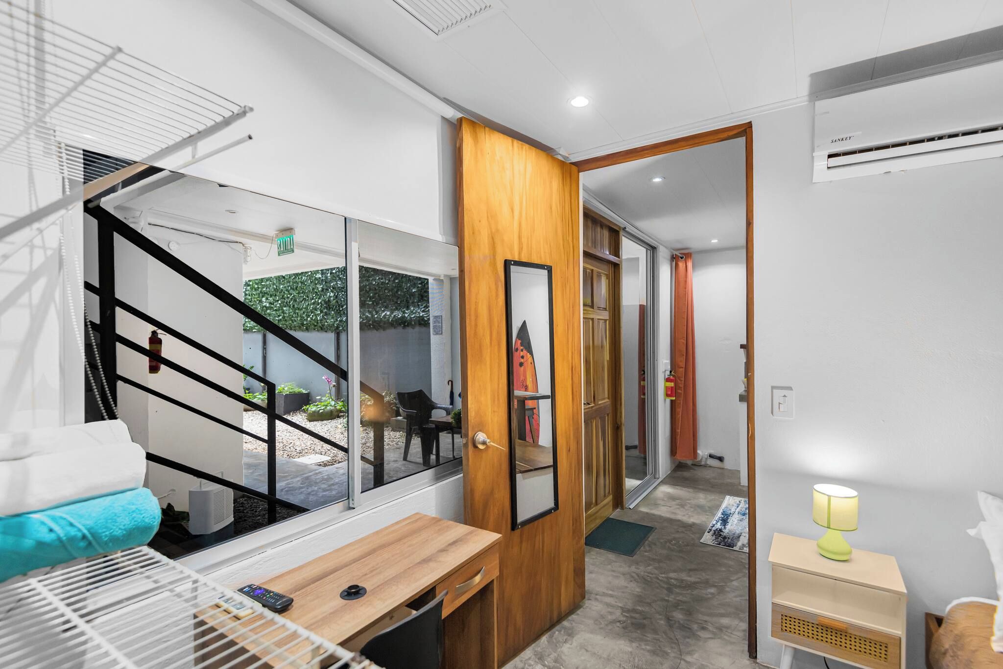 A modern interior with a wooden door, a small table, a bench, and a bed with a headboard.
