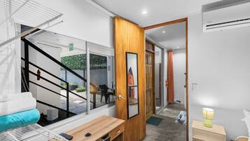 A modern interior with a wooden door, a small table, a bench, and a bed with a headboard.