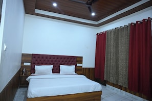 A bedroom with a wooden headboard, a bed with white bedding, a nightstand, and a red curtain.
