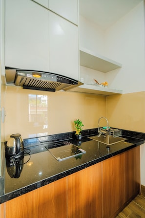 Cozinha moderna com bancada preta, eletrodomésticos de aço inoxidável e forno embutido.