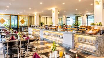 A hotel breakfast area with buffet-style food, seating arrangements, and a view of the outdoors.