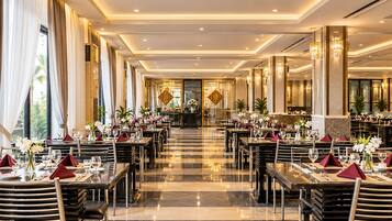 A spacious hotel dining area with multiple tables, chairs, and a central decorative element.