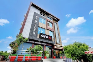 Un hotel de varios pisos con fachada moderna, amplios ventanales y un letrero llamativo que dice 'OYO Hotel and Restaurant Rajputana'.